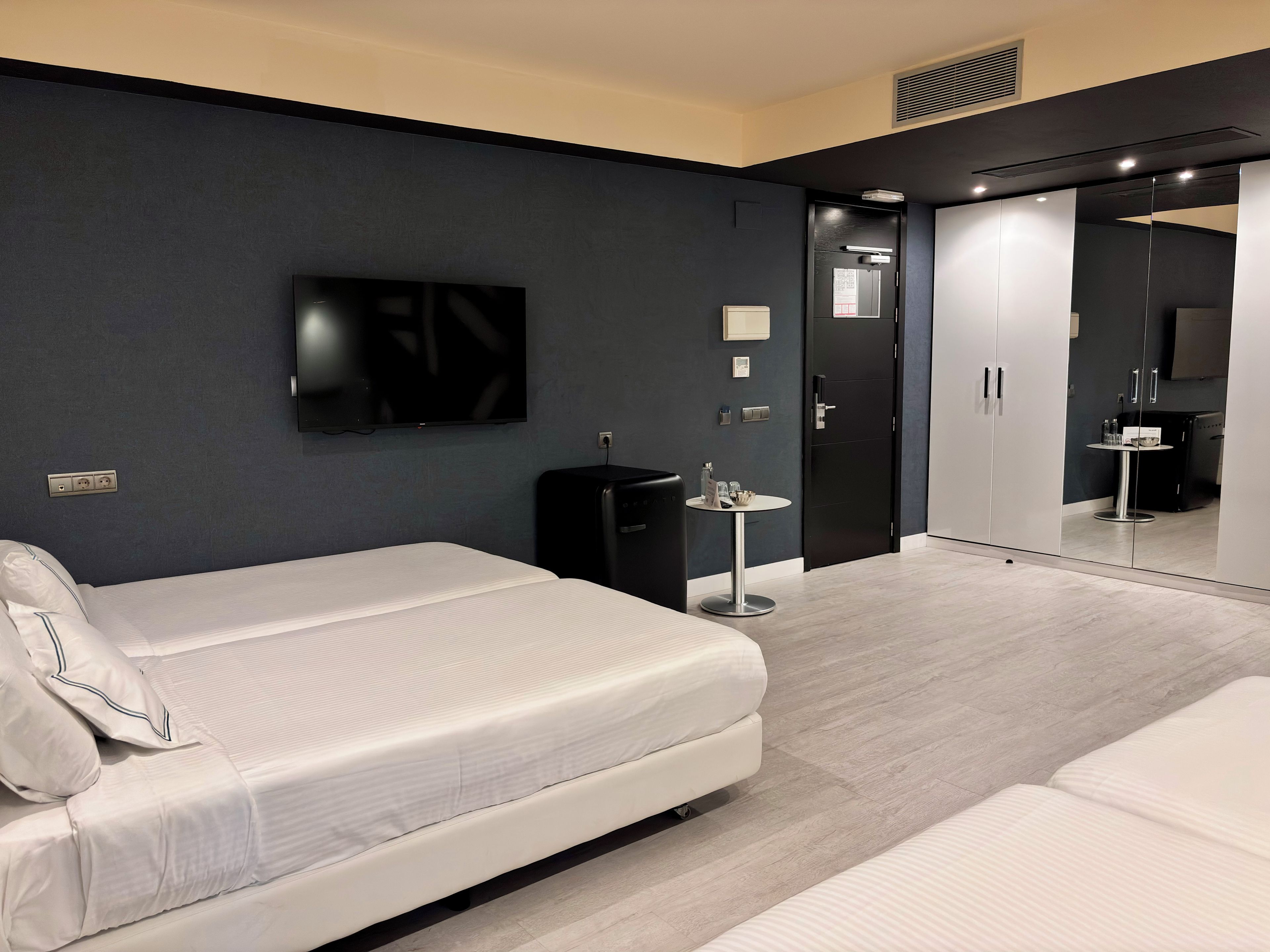 Een moderne hotelkamer met een bed, een tafeltje, een televisie en een kledingkast.