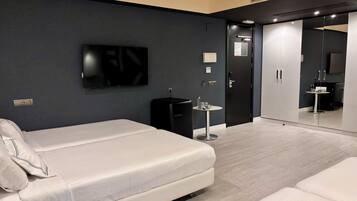Una habitación de hotel moderna con cama, una mesita, un televisor y un armario.
