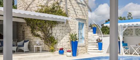 Een buitenzwembad, parasols bij het zwembad en ligstoelen