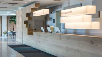 A reception desk with a modern design, featuring a wooden panel and a sign that reads "Konferansecenter".
