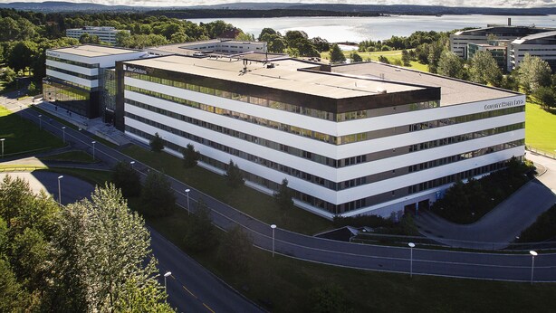 A modern hotel with a flat roof, multiple floors, and a large parking area.
