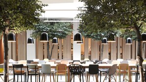 An indoor dining area with tables and chairs, wooden accents, and hanging pendant lights.
