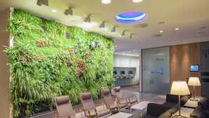 A modern lobby with a green vertical garden, seating area, and a reception desk.