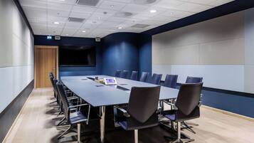 A conference room with a long table, chairs, and a projector screen.