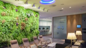 A modern lobby with a green vertical garden, seating area, and a reception desk.