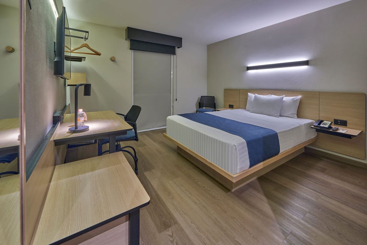 Una habitación de hotel con cama, escritorio, silla y televisor.