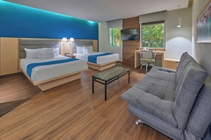Habitación de hotel con dos camas, un sofá, un escritorio y un televisor.