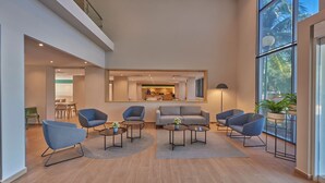 A spacious living area with modern furniture, a large window with a view, and a kitchen in the background. - City Express by Marriott Playa Del Carmen (Playa del Carmen)