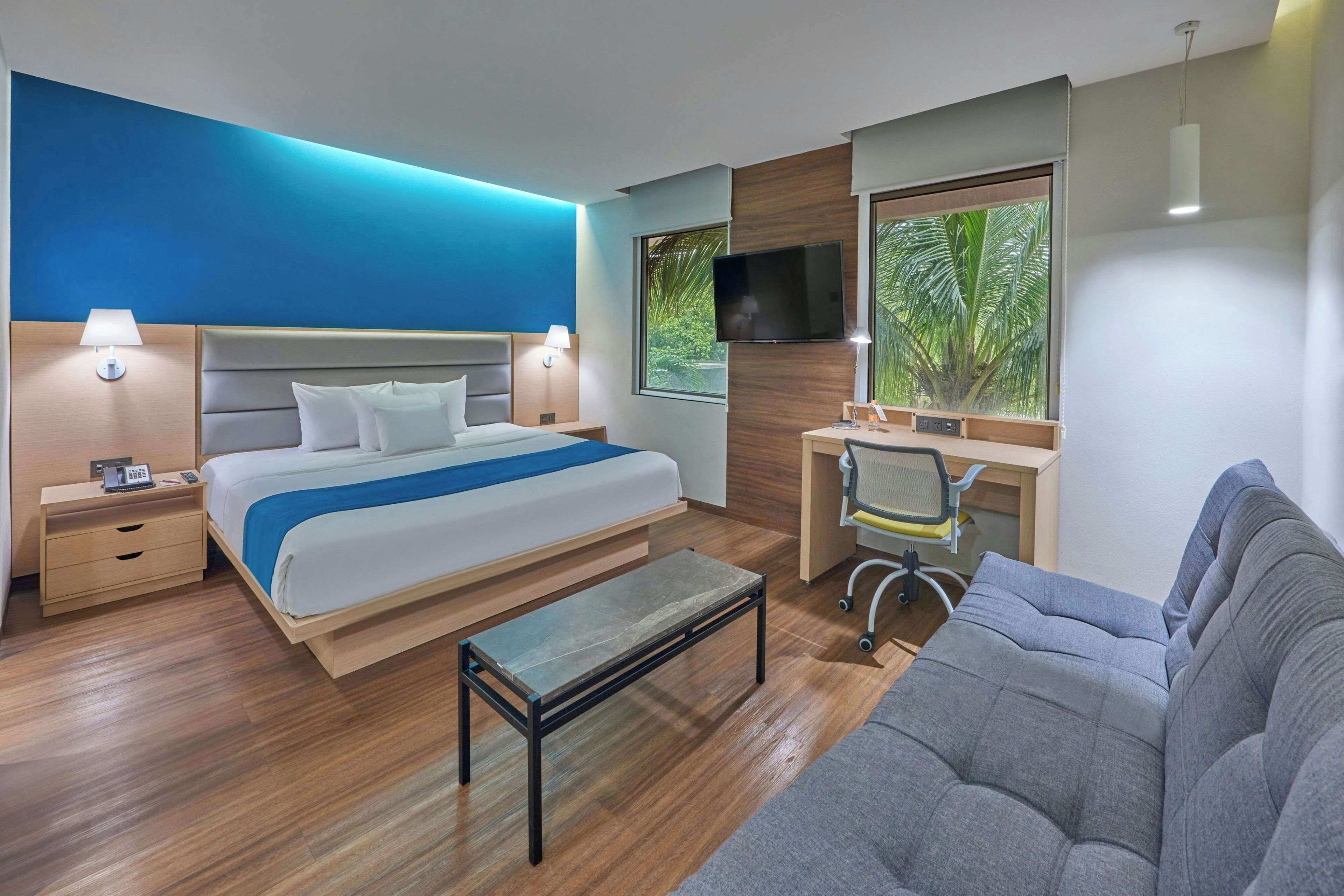 Une chambre d’hôtel moderne équipée d’un lit, d’un bureau et d’un coin salon.