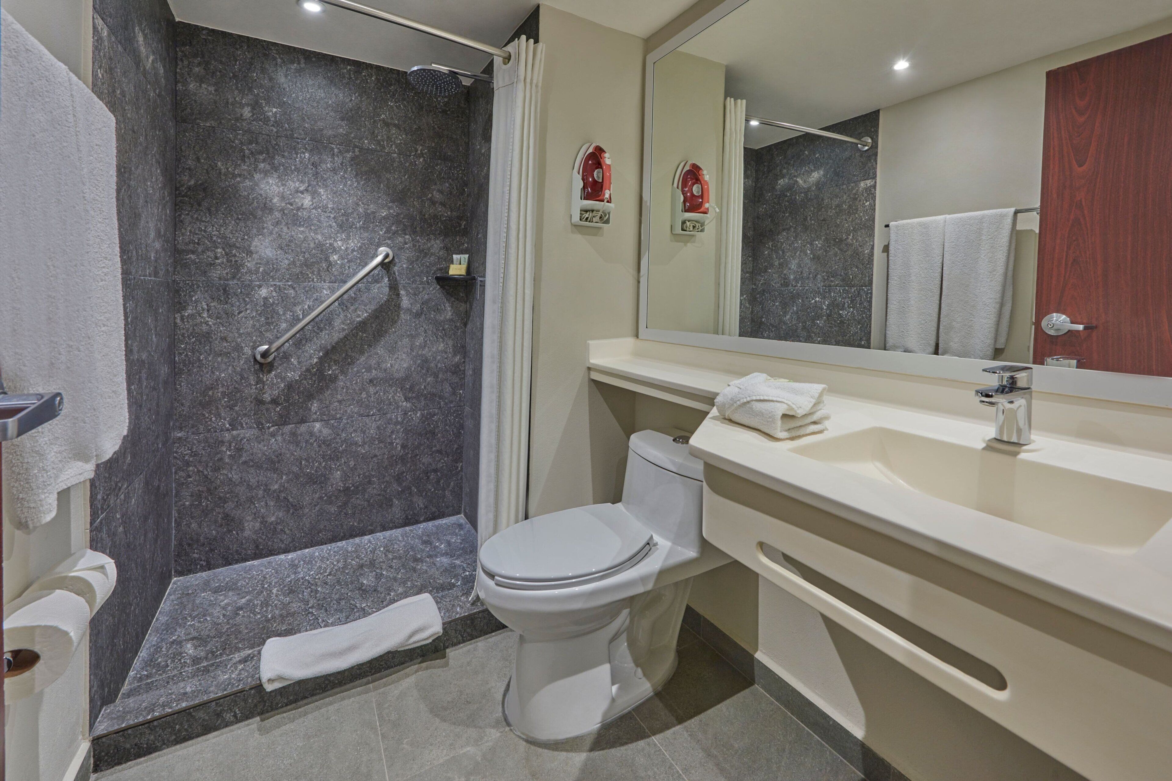 Een moderne badkamer met een douche, toilet en wastafel.