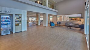 A spacious lobby with a modern design, featuring a 'Grab&Go' kiosk, seating areas, and a view of the kitchen area. - City Express by Marriott Playa Del Carmen (Playa del Carmen)