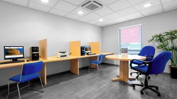 Een moderne kantoorruimte met bureaus, stoelen, computers en een groot raam.