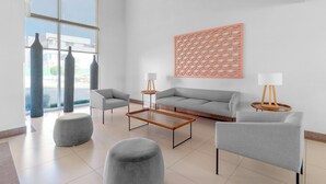 Un salon moderne avec un canapé gris, deux fauteuils, une table basse et un élément décoratif mural.