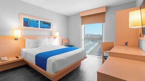 Une chambre d’hôtel moderne dotée d’un grand lit, de tables de chevet, d’un bureau et offrant une vue sur la ville.