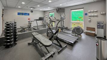 Un gimnasio con diversos equipos de ejercicio, incluyendo cintas de correr, máquinas elípticas y pesas libres.
