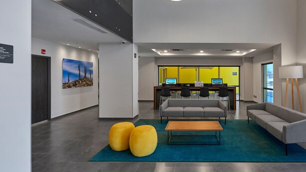 A modern lobby with a reception desk, seating area, and a large window. - City Express by Marriott Puebla Finsa (Cuautlancingo)