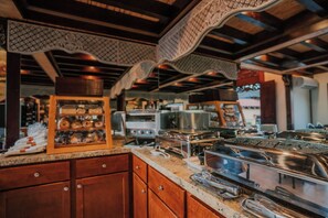 A kitchen with wooden cabinets, stainless steel appliances, and a display case with baked goods.