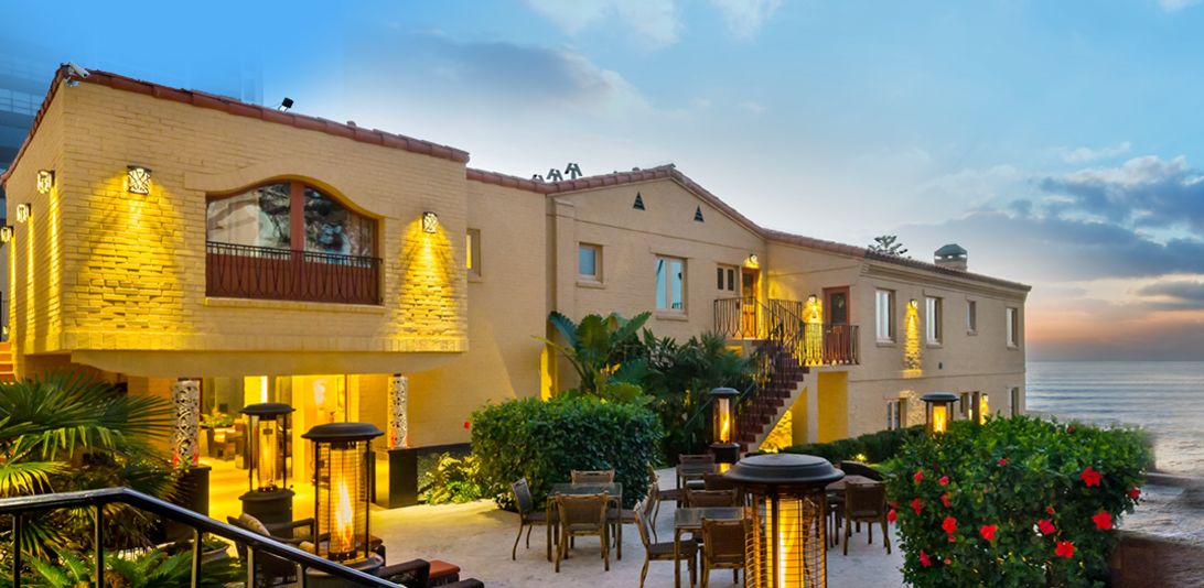A hotel with a patio area featuring outdoor seating and a view of the sea.