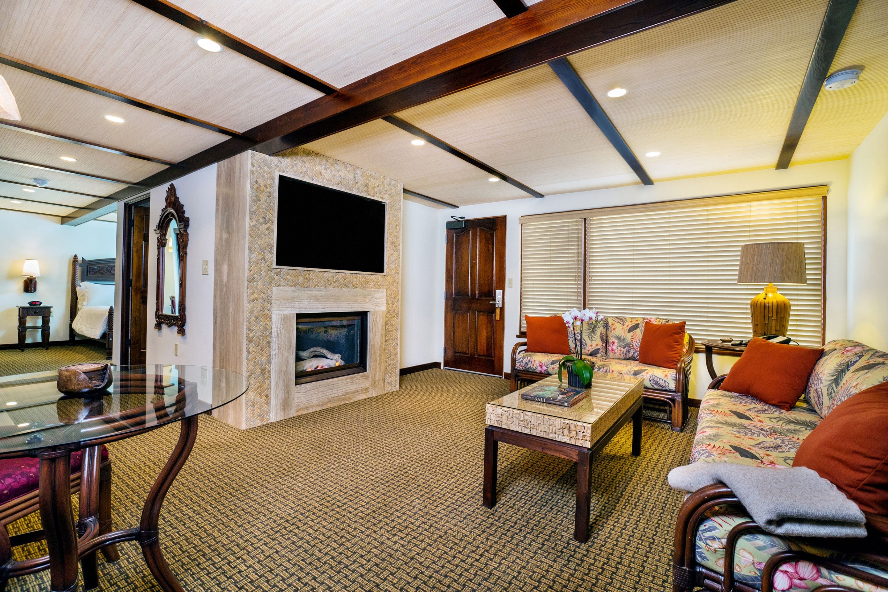 A spacious living room with a fireplace, comfortable seating, and a glass coffee table.