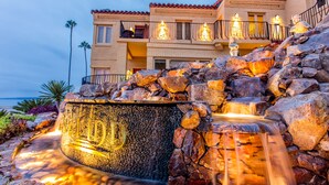 A hotel with a water feature, stone steps, and balconies with lights. - Pantai Inn (La Jolla)