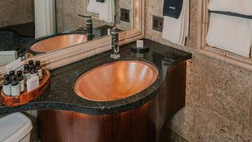 A bathroom with a large mirror, two sinks, and a vanity with a copper basin.