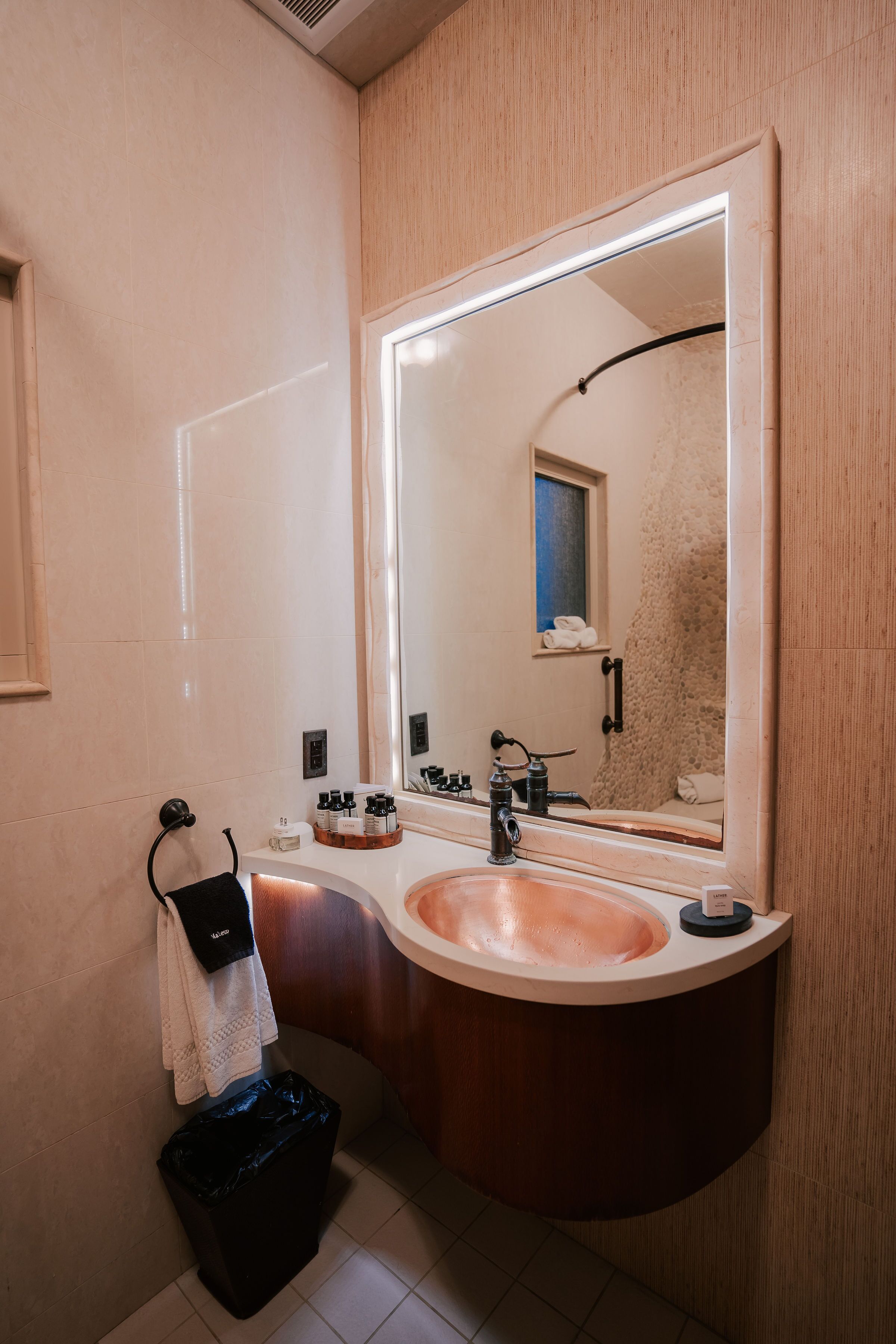 A bathroom with a large mirror, a sink, and a towel rack.