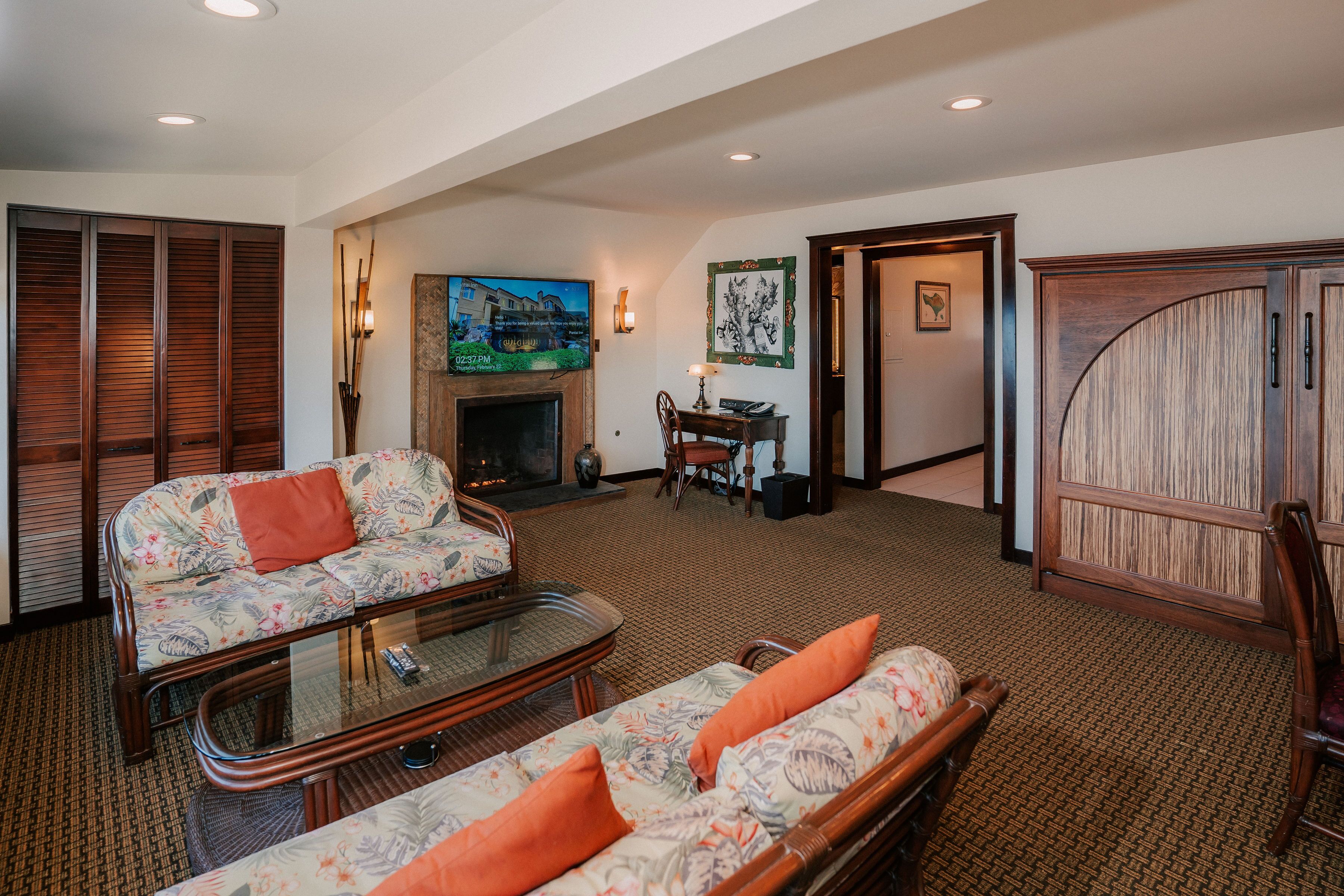 A spacious living room with a sofa, a glass coffee table, and a fireplace.