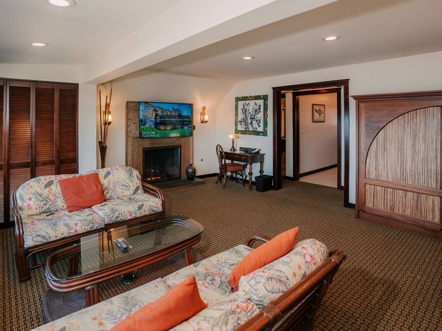 A spacious living room with a sofa, a glass coffee table, and a fireplace.