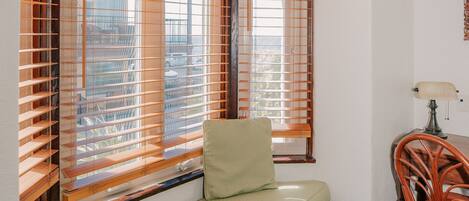 A corner room with a built-in bench, a chair, and a window with blinds.