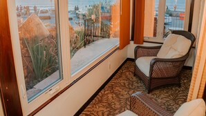 A balcony with wicker furniture, large windows, and a ceiling fan. - Pantai Inn (La Jolla)