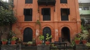 Un bâtiment de style colonial doté de trois portes cintrées et d’un balcon.