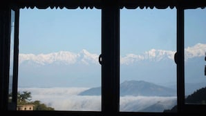 Une fenêtre donnant sur des montagnes enneigées et une vallée en contrebas.