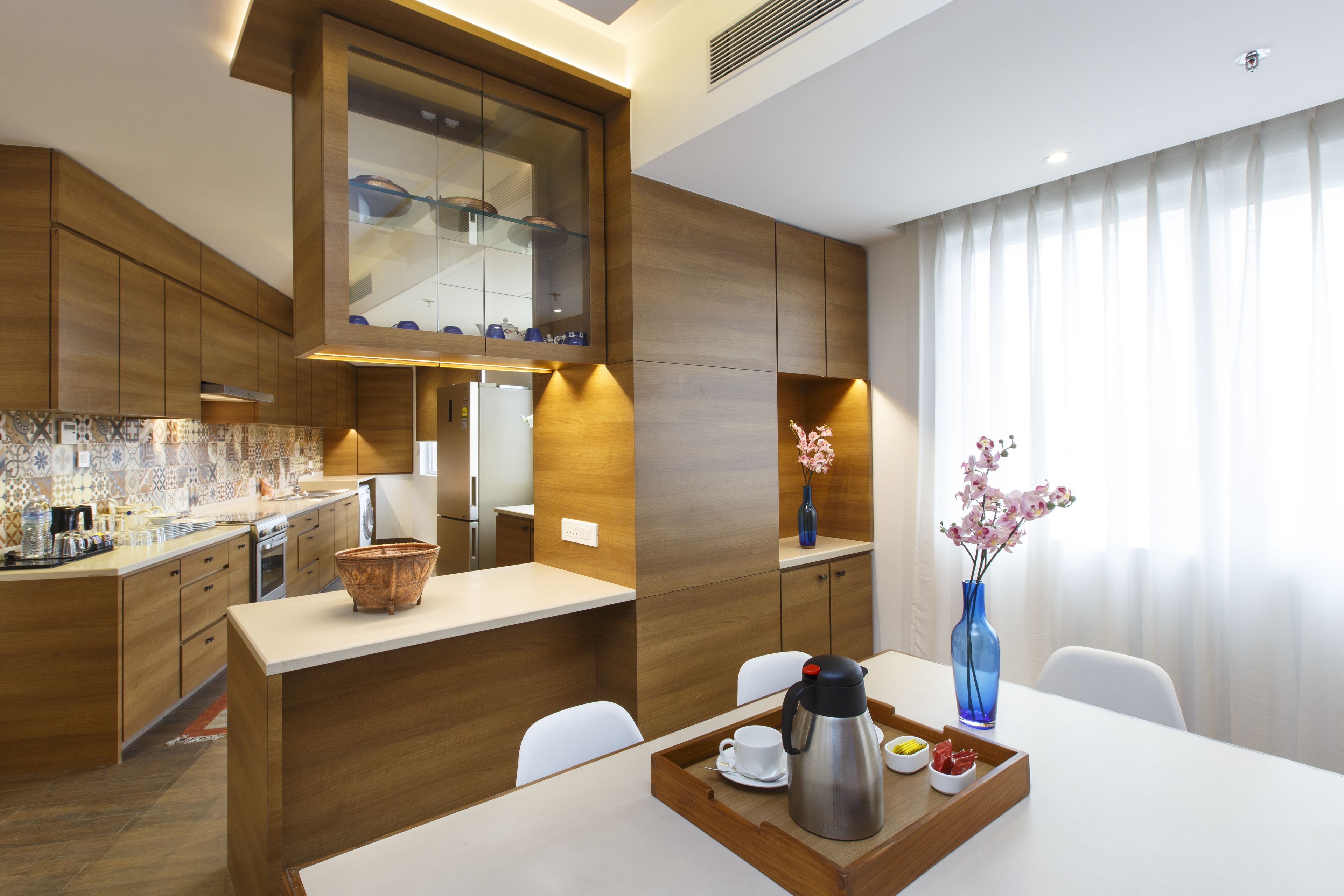 A modern kitchen with wooden cabinetry, a central island, and a dining area with a tray of breakfast items.