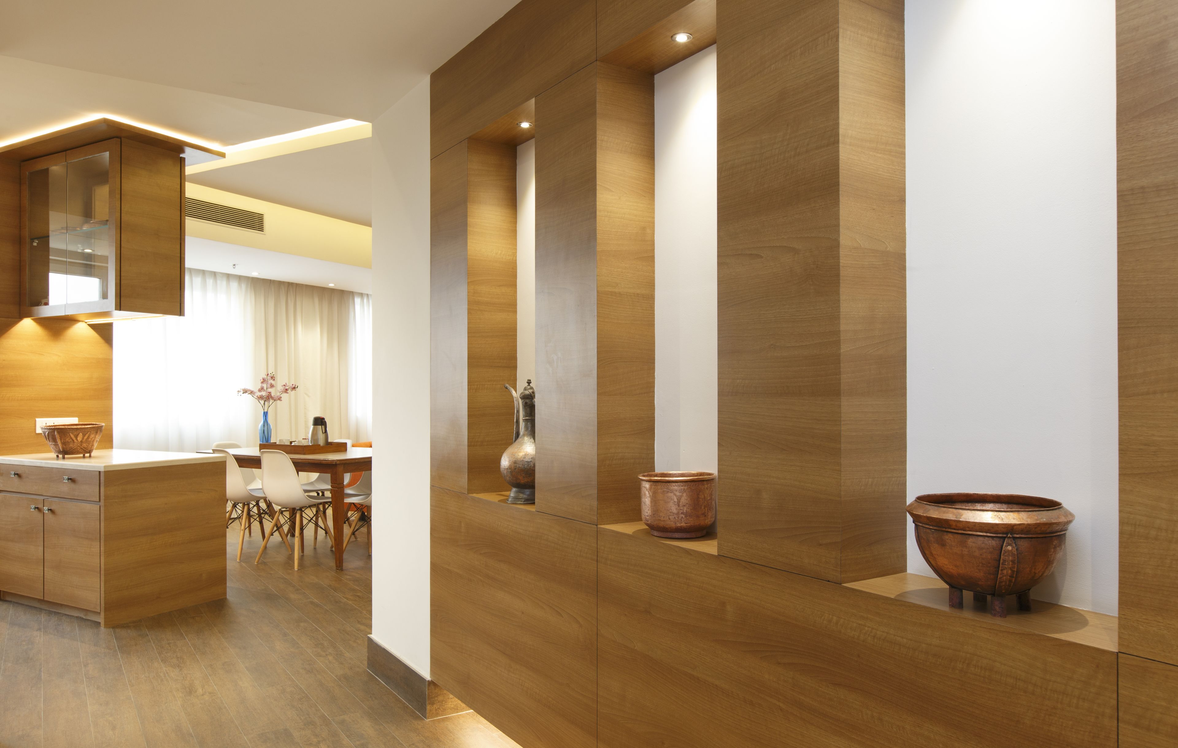 A modern kitchen with wooden cabinetry, a dining area with a table and chairs, and a large window with curtains.