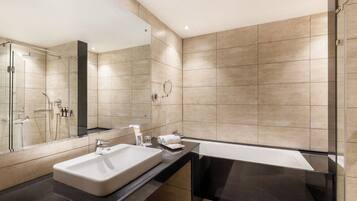 A modern bathroom with a large sink, a bathtub, and a glass-enclosed shower.