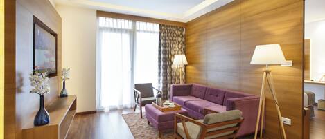 Un salon moderne avec un canapé violet, un plancher en bois et un lampadaire.