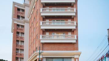 Un edificio de varios pisos con balcones, una entrada protegida por una reja y una fachada bien iluminada.