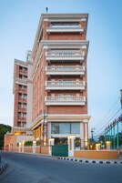 Un edificio de varios pisos con balcones, una entrada protegida por una reja y una fachada bien iluminada.