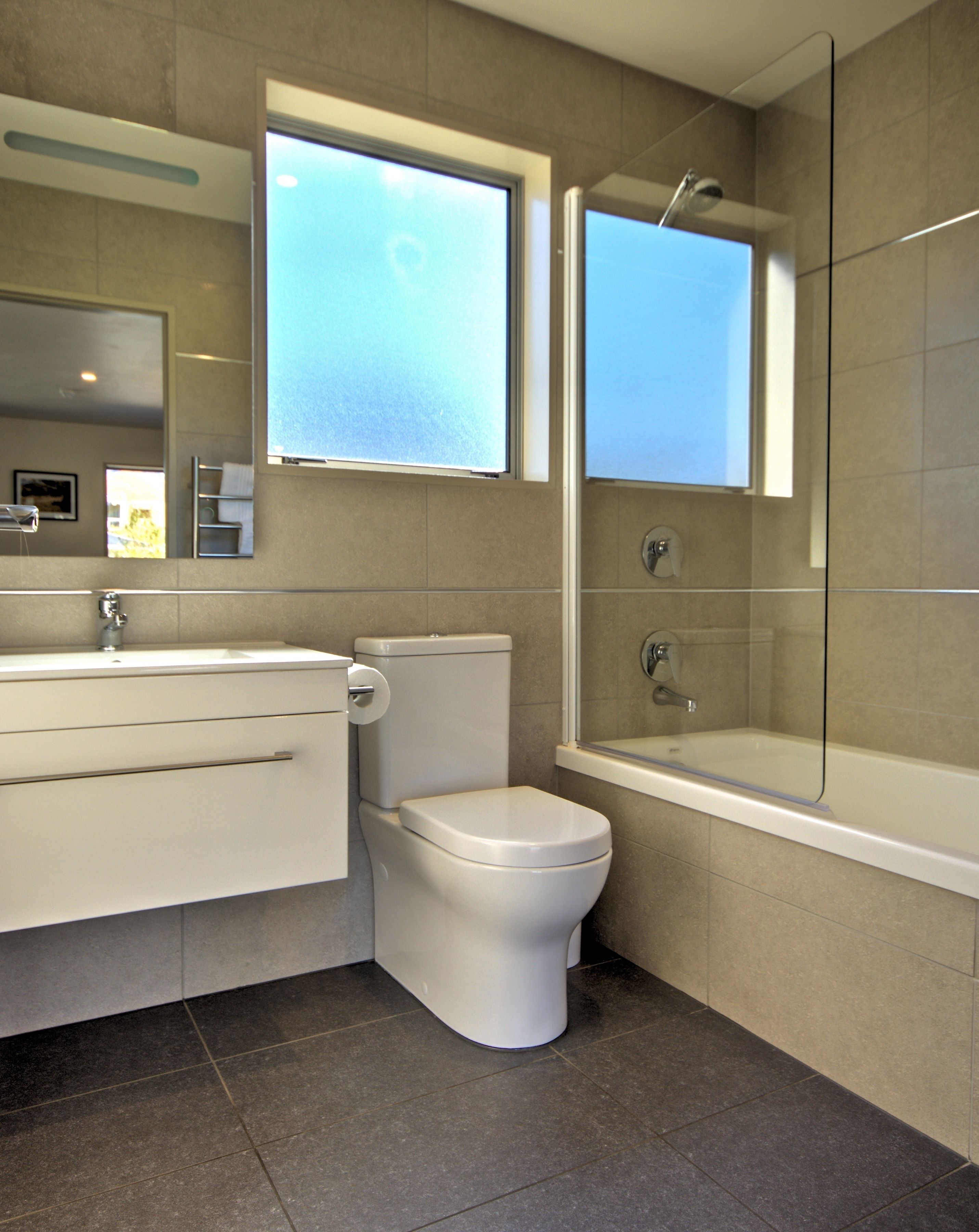A modern bathroom with a toilet, sink, and bathtub.