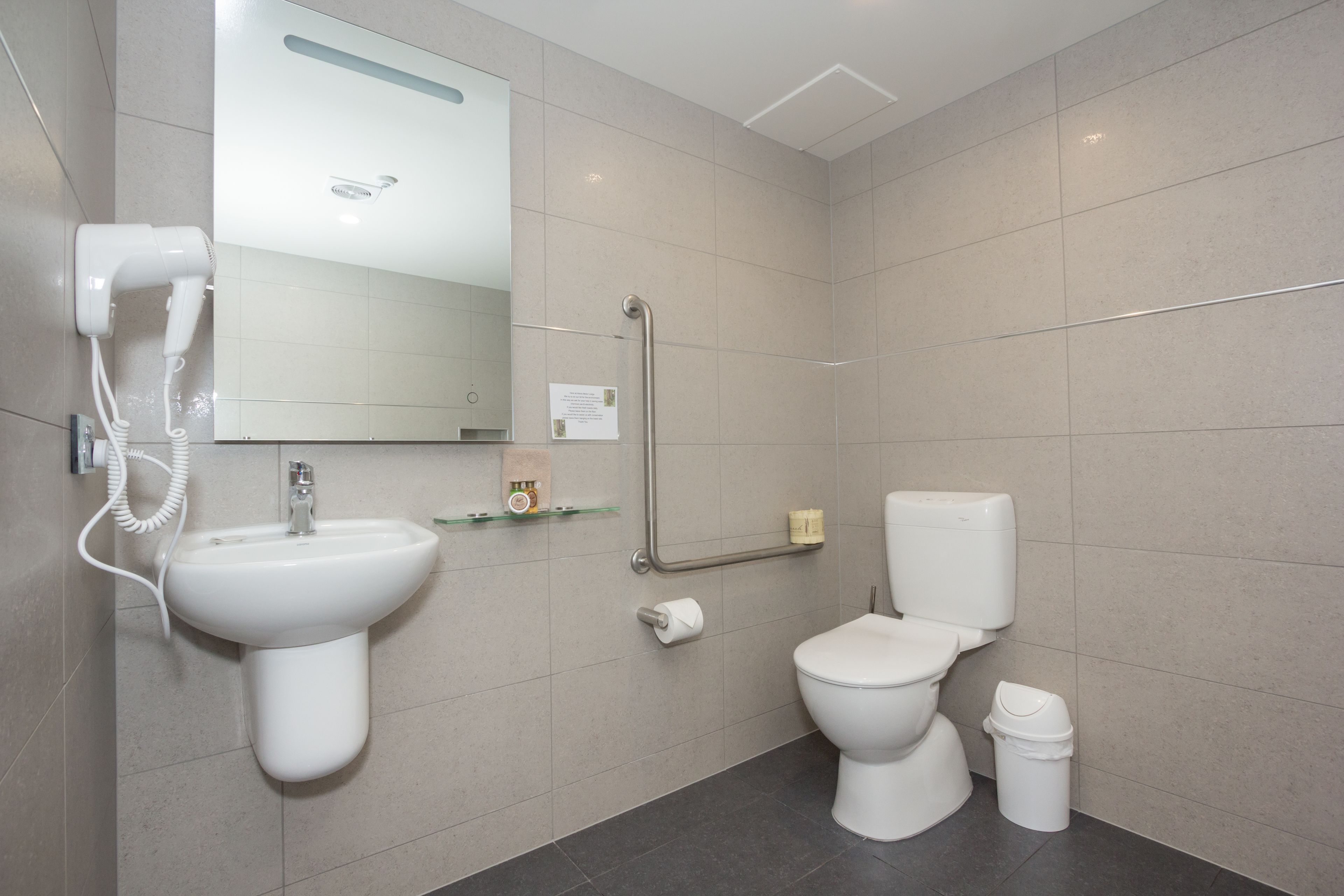 Un baño moderno con lavamanos, inodoro y secamanos.