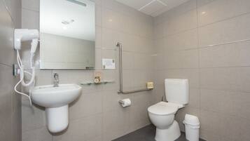 Un baño moderno con lavamanos, inodoro y secamanos.