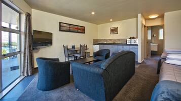 Una habitación de hotel compacta con sofá, una mesa de comedor y kitchenette.