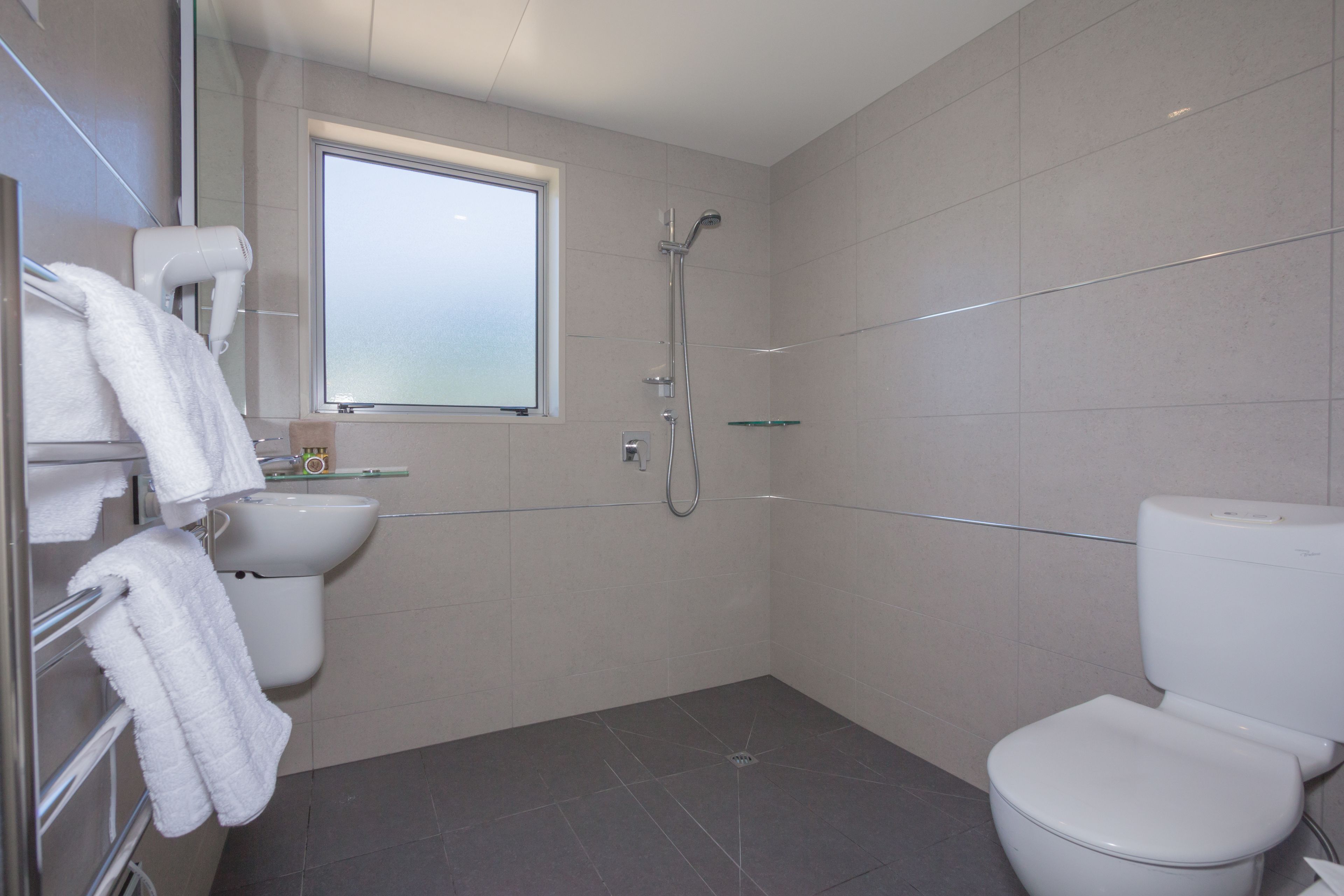 A modern bathroom with a toilet, sink, and shower.
