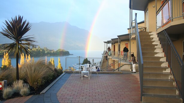 Ein Gebäude mit einer Treppe, Blick auf einen See und einem Regenbogen.