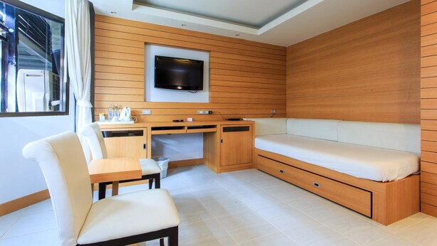Ein kleines Zimmer mit einem Bett, einem Schreibtisch und einem an der Wand befestigten Fernseher.