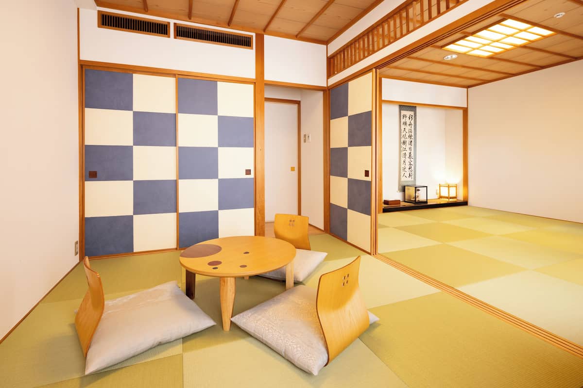A traditional Japanese room with tatami flooring, a low wooden table with cushions, and shoji screens.