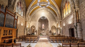A church interior with a central aisle, pews, and a large pipe organ. - Notre Dame of Jerusalem Center (Jerusalem)