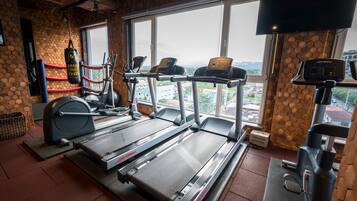 A gym with treadmills, a punching bag, and a TV screen.