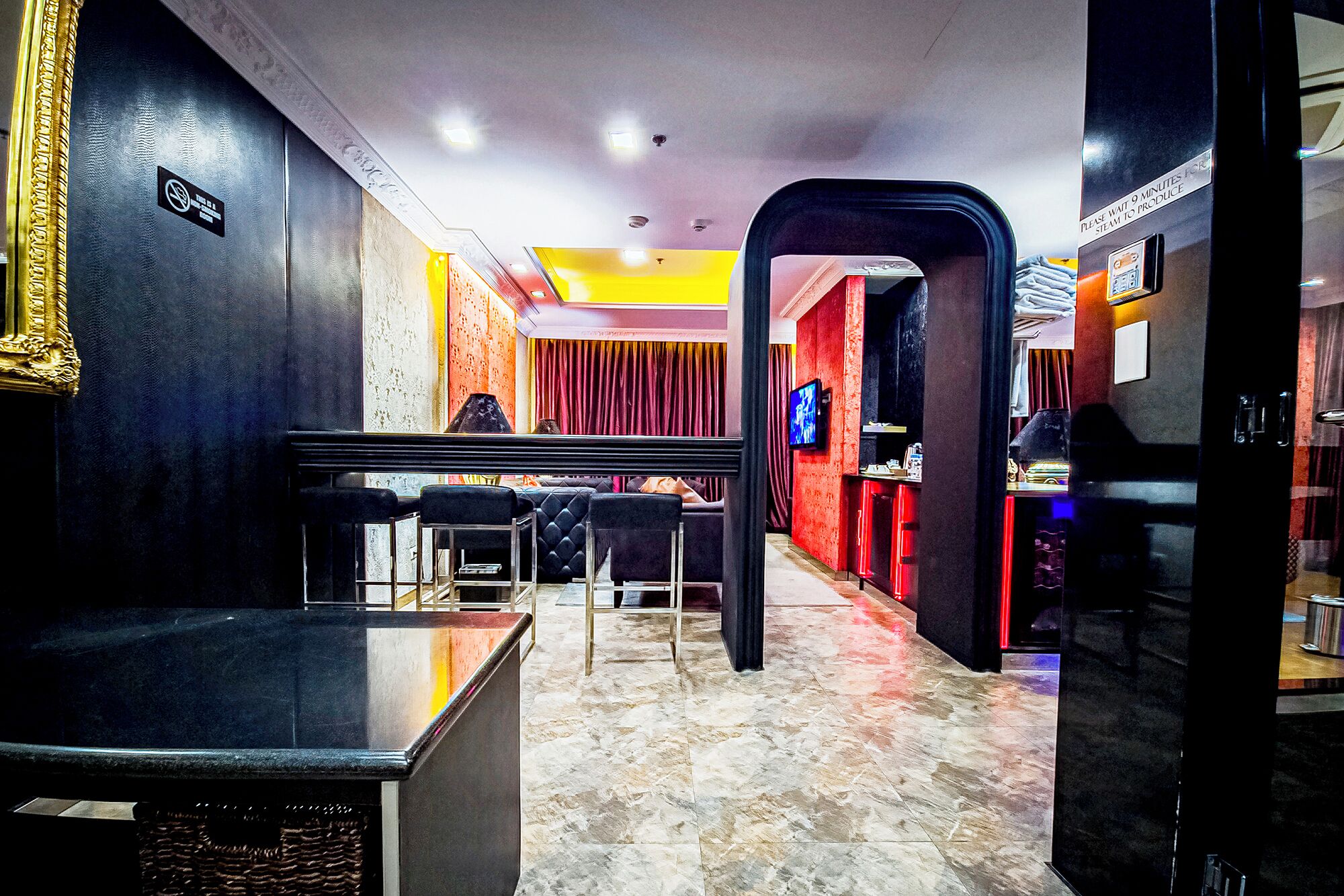Un hall de hotel con mostrador de recepción, zona de estar y pantalla de televisión.