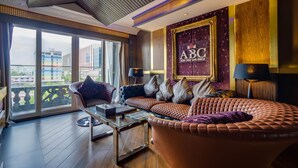 A spacious living room with a large window, a sofa set, a coffee table, and a wall-mounted sign.